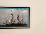 a picture of a sailboat on the wall above a bed
