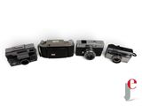 three old cameras sitting next to each other on a white surface