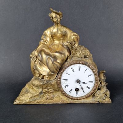 une statue représentant une femme assise sur un rocher, avec une horloge devant elle