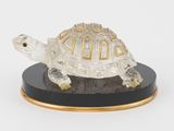 figurine représentant une tortue sur un socle noir, sur fond blanc