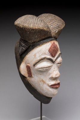 une image représentant un masque en bois posé sur un socle, sur fond gris