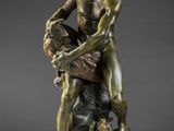 une statue en bronze représentant un homme tenant un enfant sur un rocher