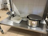 table en acier inoxydable sur laquelle sont posés des casseroles et des poêles, dans une cuisine professionnelle