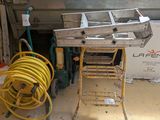 Les tuyaux jaunes se trouvent sur un chariot dans un garage, à côté d'une pile de cartons