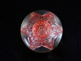 a glass object with a red design on it