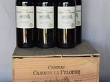 quatre bouteilles de vin rouge dans une caisse en bois posée sur une table