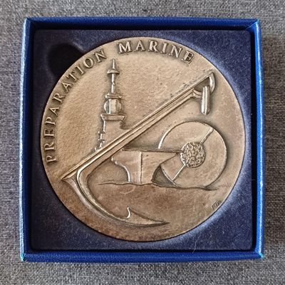une image représentant une médaille en métal sur laquelle figurent un bateau et un drapeau