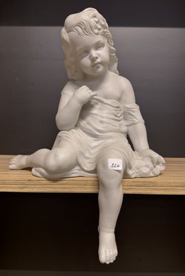 une petite statue représentant un enfant assis sur une étagère
