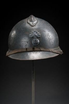 an old helmet on a metal stand with a black background
