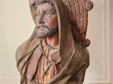 statue d'un homme coiffé d'un chapeau, assis sur un plancher en bois