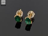 paire de boucles d'oreilles en émeraude sur un fond noir avec reflets