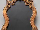 an ornately carved mirror with a black background and a gold frame