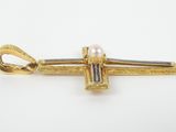 an image of a gold and pearl pin with a cross on it
