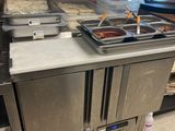Plusieurs plateaux de plats sont alignés sur le comptoir d'un restaurant