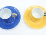 two cups and saucers sitting on a white surface