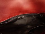 a red purse with a black handle on a table