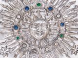 a silver brooch with a face surrounded by stars
