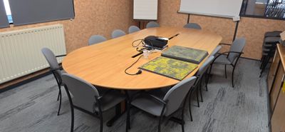 des tables et des chaises dans une salle de conférence équipée d'un projecteur et d'un écran de projection