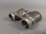 pair of antique silver binoculars sitting on top of a table