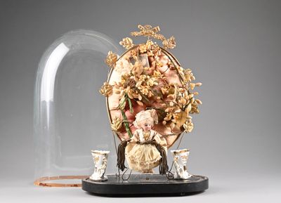 une cloche de verre sous laquelle se trouvent une figurine représentant une femme et deux chats