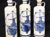 trois vases bleus et blancs ornés de moulins à vent sur fond noir