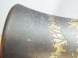 un vase noir orné de motifs dorés, tenu dans la main de quelqu'un