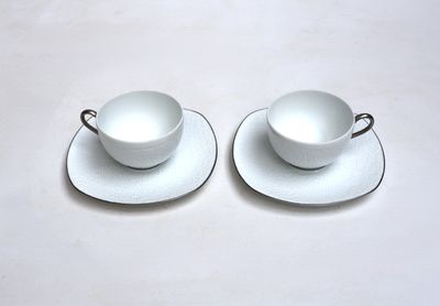 two cups and saucers sitting on a white table