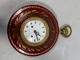 a red and gold clock sitting on a white table