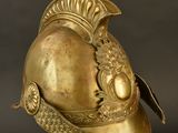 a gold helmet on a stand against a black background