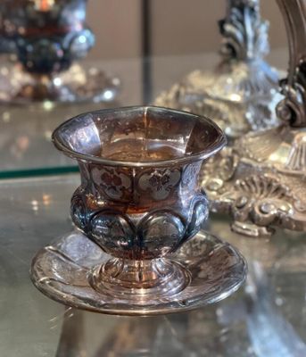a glass cup and saucer sitting on a glass table