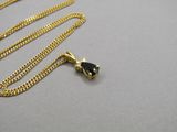 chaîne en or jaune avec un pendentif en pierre noire sur un fond gris