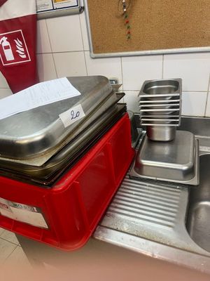 Plusieurs casseroles et poêles sont empilées sur un plan de travail dans une cuisine.