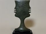 sculpture of a face on a black base with a white background