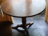 une table ronde au plateau en bois, placée devant une fenêtre