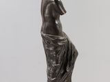 a bronze statue of a woman sitting on a marble base