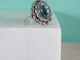 an image of a ring with a blue topaz stone surrounded by white diamonds
