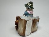 a figurine of a boy sitting on top of a book