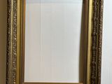 two gold frames on a white table with a wall in the background