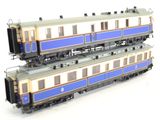 two trains that are sitting side by side on a white surface