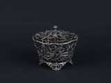 an antique silver plated bowl with a handle on a black background