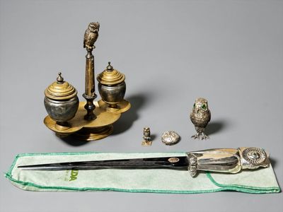 a silver plate with a bird on it next to a pair of scissors