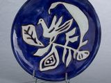 une assiette bleue ornée d'un oiseau, posée sur un socle