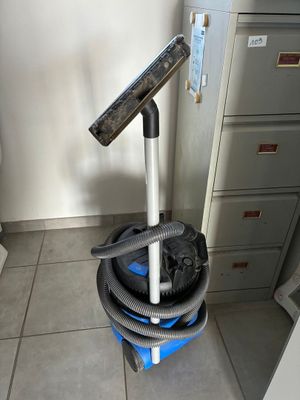 une image représentant un aspirateur posé sur un chariot bleu