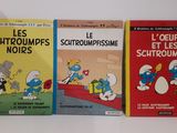 Trois livres sur les Schtroumpfs sont alignés sur une surface blanche