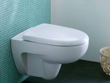 des toilettes blanches situées dans une salle de bains, à côté d'un panier rempli de papier toilette