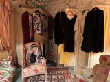 a room with a chair, a bed, and a closet with clothes on hangers