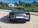 the rear end of a silver sports car parked on the side of a road