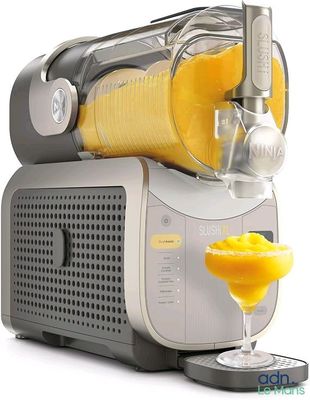 un extracteur de jus avec un verre de jus d'orange à côté