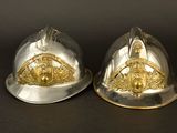 pair of silver and gold fire helmets on a black background