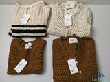 three sweaters and a bag are sitting on a table